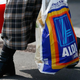 Person carrying Aldi bag out of store with basket